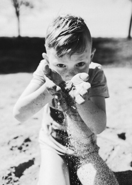 černobílá fotka dítě si hraje s pískem