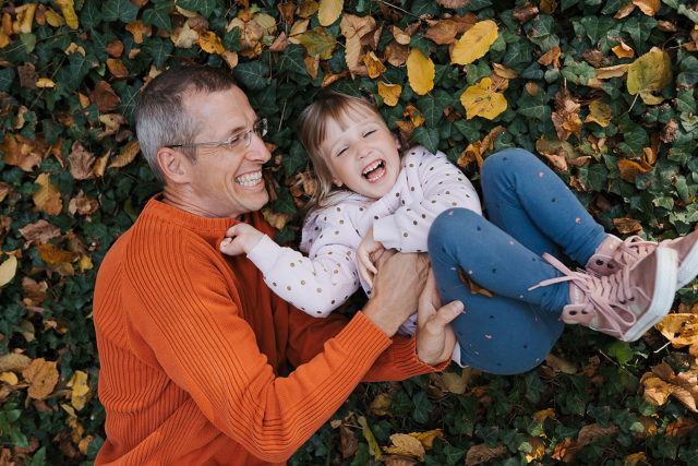rodinné foto tatínka s dcerou při hře v listí