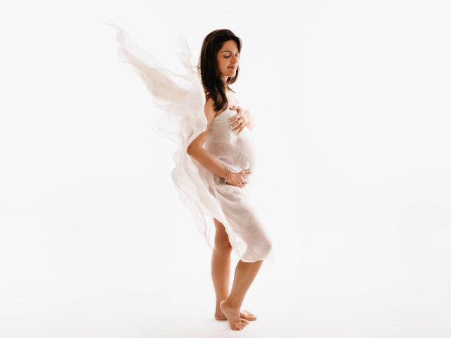 portrétní fotografie těhotné ženy v bílém vlajícím šátku va ateliéru v Praze
