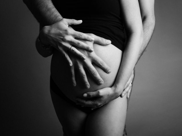 detail těhotenského bříška s rukama rodičů