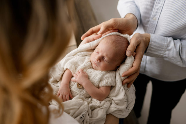 fotka novorozence v dlaních rodičů z lifestyle newborn focení v Praze v ateliéru