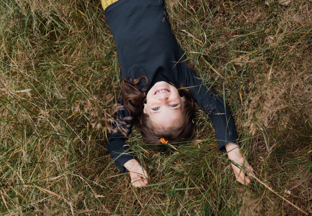 dětská portrétní fotografie díla ležící v sucha trávě